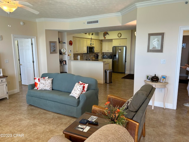 living room with ceiling fan, sink, light tile floors, a textured ceiling, and ornamental molding