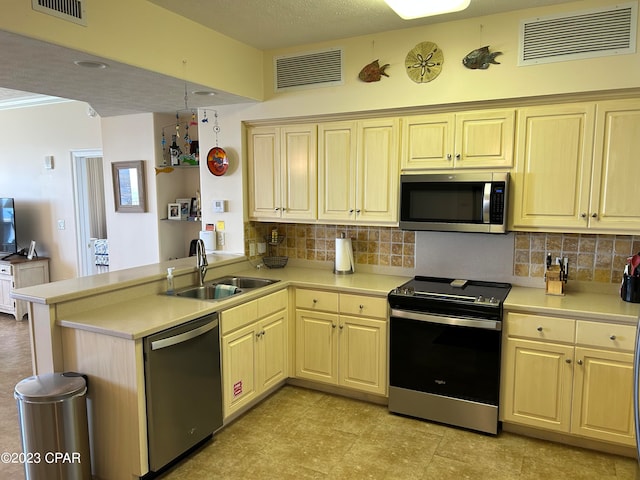 kitchen featuring kitchen peninsula, backsplash, light tile flooring, appliances with stainless steel finishes, and sink