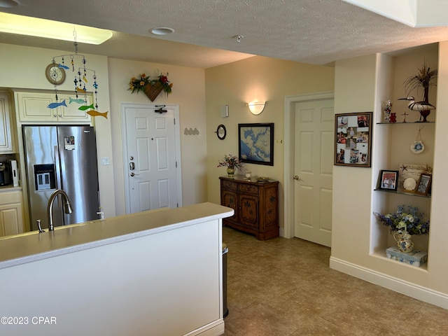 kitchen featuring stainless steel fridge, hanging light fixtures, light tile floors, and a textured ceiling