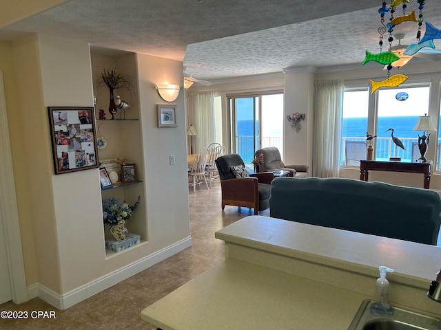 living room featuring a water view, light tile floors, and a textured ceiling