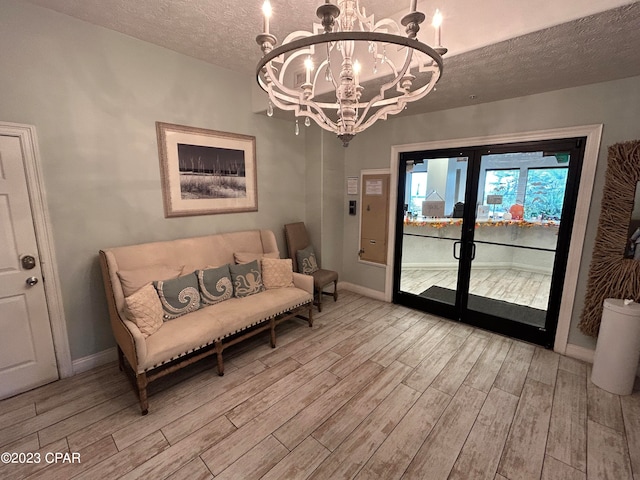 living area with a textured ceiling, a notable chandelier, and light wood-type flooring