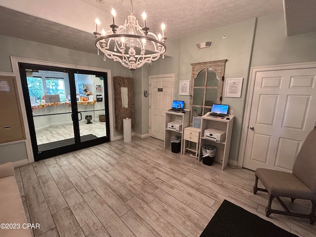 interior space with an inviting chandelier, a textured ceiling, and light hardwood / wood-style flooring