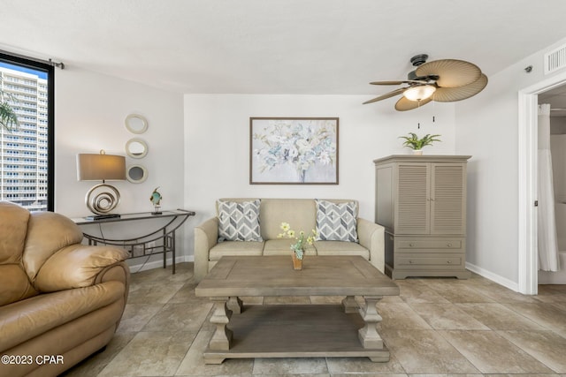 living area with a ceiling fan, visible vents, and baseboards