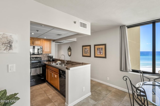 kitchen with dark countertops, visible vents, a sink, a peninsula, and black appliances