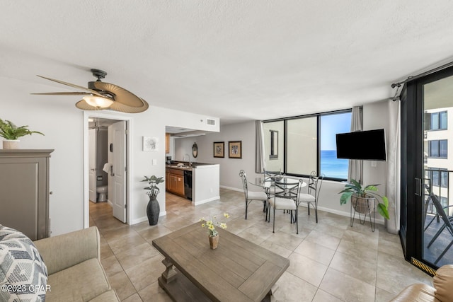 living area featuring a textured ceiling, light tile patterned floors, visible vents, baseboards, and a ceiling fan