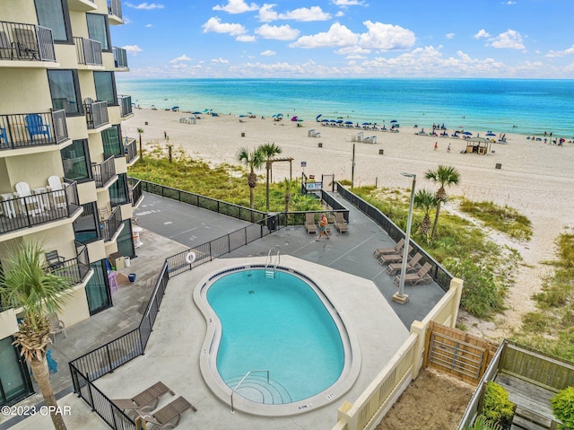 community pool featuring a water view, fence, and a view of the beach