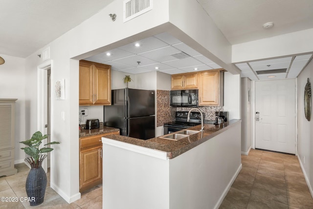 kitchen featuring light tile patterned floors, visible vents, a peninsula, black appliances, and backsplash