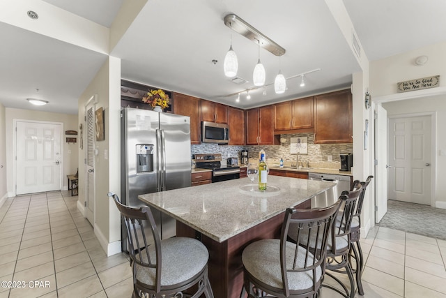 kitchen featuring a sink, light tile patterned floors, appliances with stainless steel finishes, and backsplash