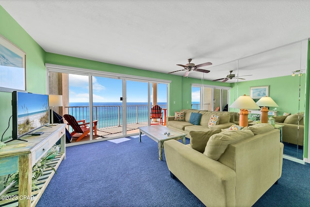 living room with ceiling fan, dark carpet, and a textured ceiling