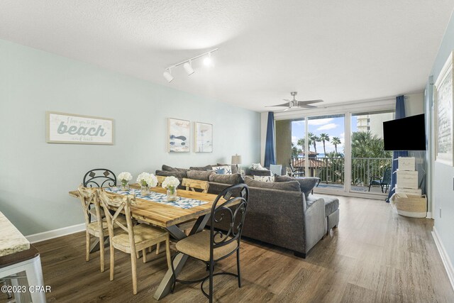 dining space with rail lighting, ceiling fan, a textured ceiling, and dark wood-type flooring