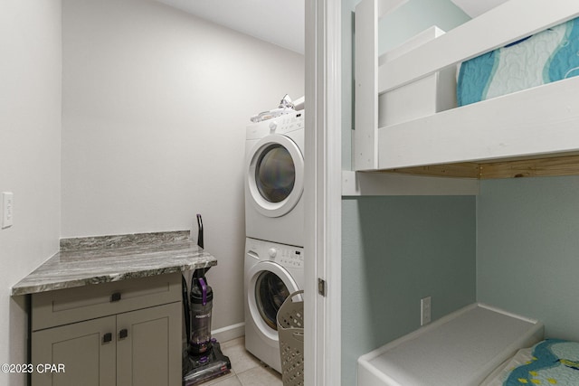 laundry room featuring stacked washer / dryer and light tile patterned flooring