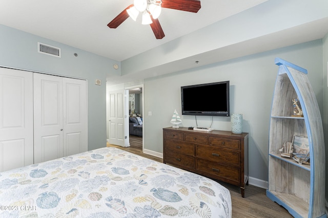 bedroom with ceiling fan, dark wood-type flooring, and a closet