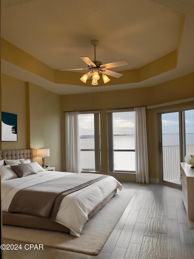 bedroom featuring a tray ceiling, access to exterior, and ceiling fan