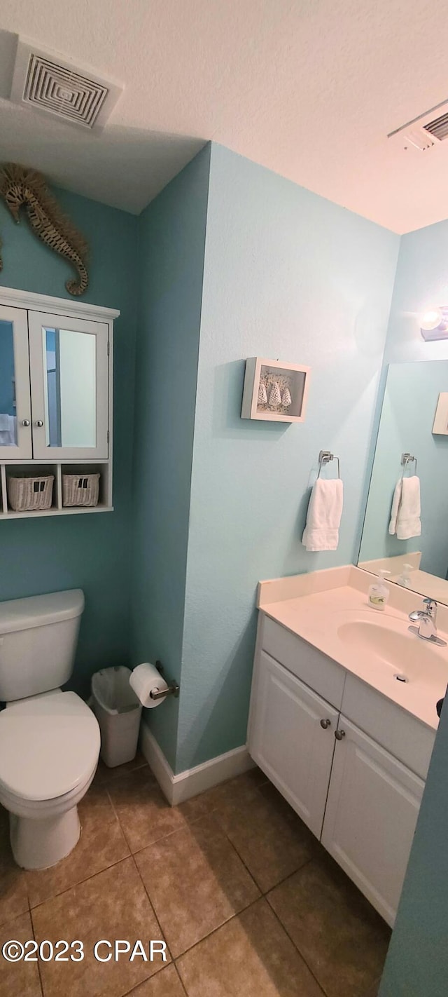 bathroom featuring toilet, vanity, and tile flooring