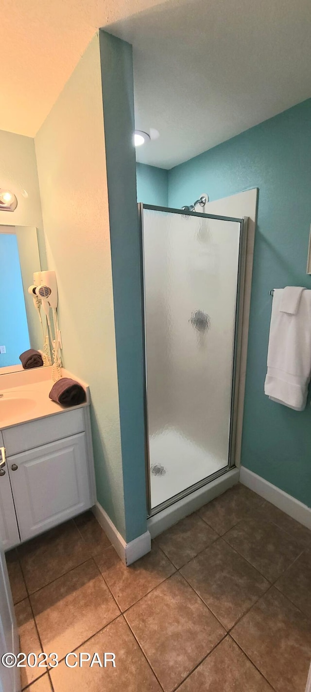 bathroom featuring tile flooring, a shower with shower door, and vanity