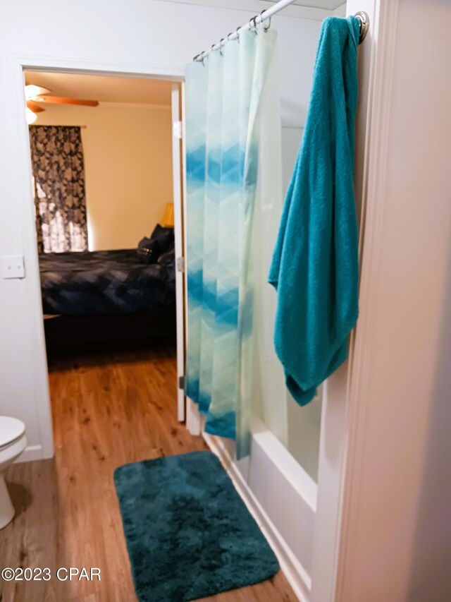 bathroom with ceiling fan, toilet, wood-type flooring, and shower / tub combo