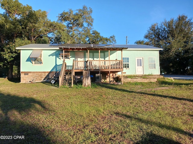 rear view of property featuring a lawn, solar panels, and a deck