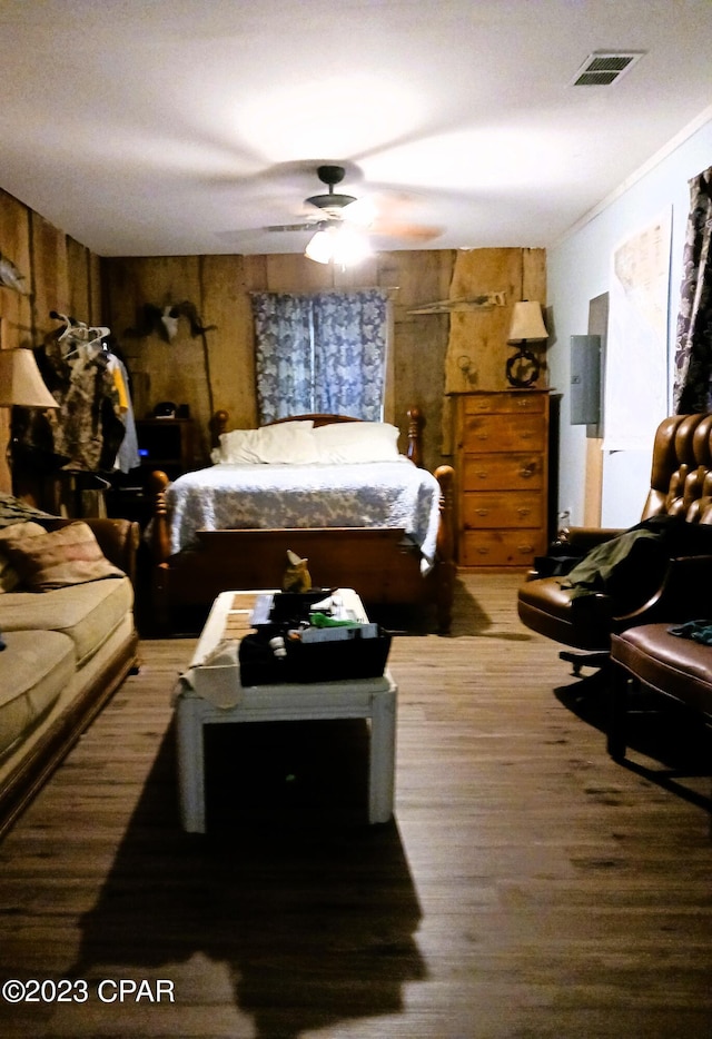 bedroom featuring ceiling fan and wooden walls