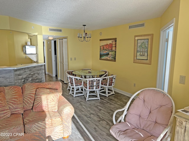 dining space with an inviting chandelier, hardwood / wood-style floors, and a textured ceiling