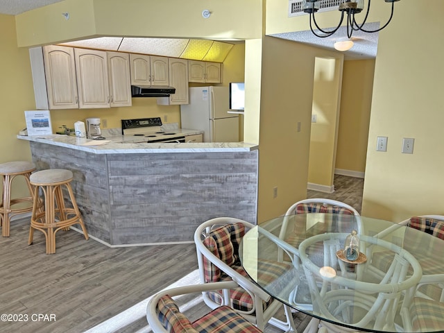 kitchen featuring white appliances, kitchen peninsula, light hardwood / wood-style flooring, and a notable chandelier