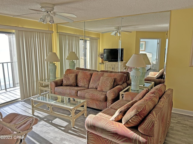 living room with ceiling fan, a textured ceiling, and light wood-type flooring