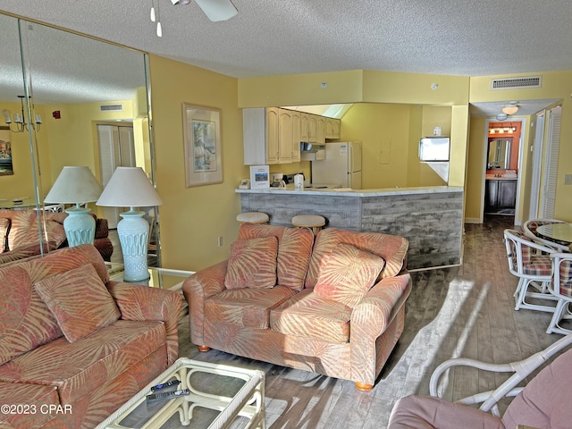 living room with ceiling fan, wood-type flooring, and a textured ceiling