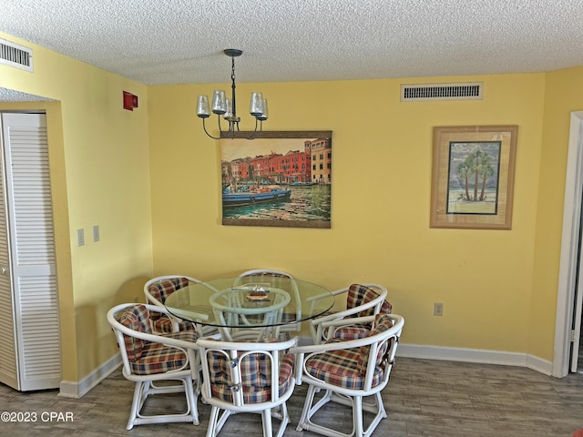 dining space with dark hardwood / wood-style flooring, a textured ceiling, and a notable chandelier