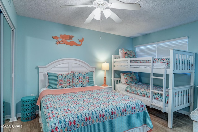 bedroom with hardwood / wood-style floors, a textured ceiling, a closet, and ceiling fan