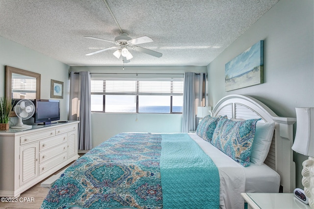 bedroom featuring ceiling fan, light hardwood / wood-style floors, a textured ceiling, and multiple windows