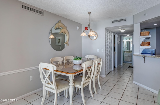 dining space featuring light tile patterned floors, a textured ceiling, and a notable chandelier