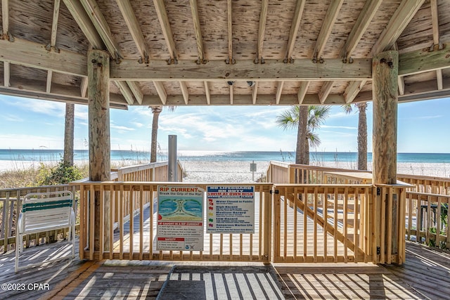 wooden deck featuring a water view and a view of the beach