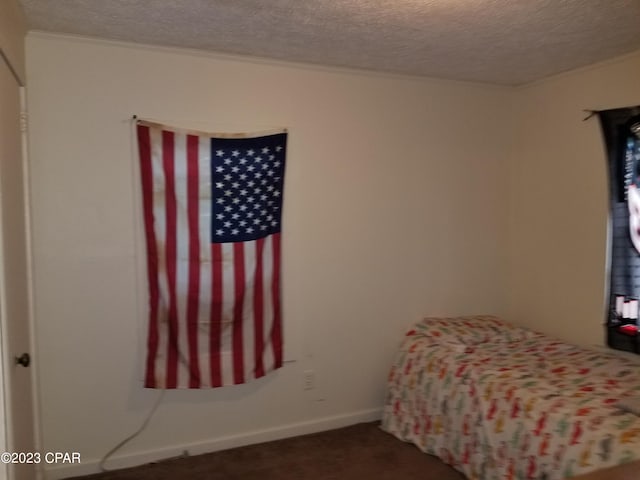 bedroom featuring a textured ceiling and dark carpet