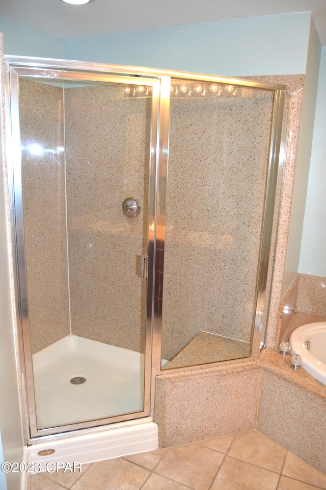 bathroom featuring a stall shower, tile patterned flooring, and a tub