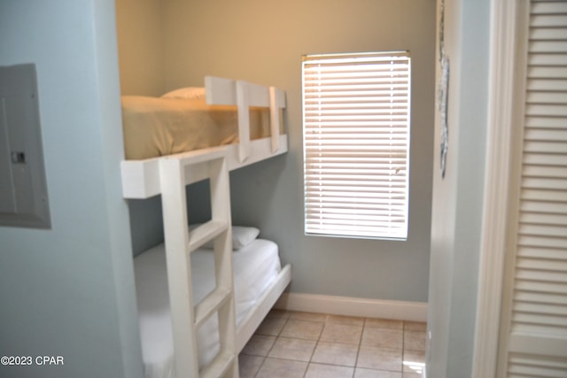 bedroom with electric panel, light tile patterned flooring, and baseboards