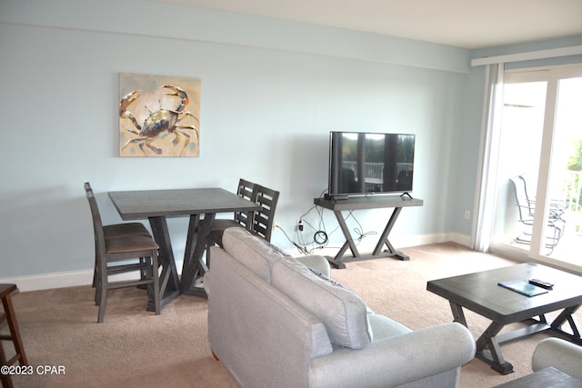 living area with baseboards and light colored carpet