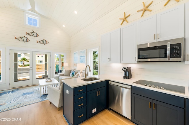 kitchen featuring appliances with stainless steel finishes, white cabinetry, french doors, sink, and high vaulted ceiling