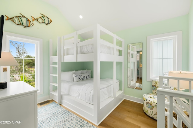 bedroom with light wood-type flooring and lofted ceiling