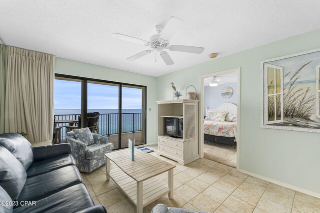 living room with a textured ceiling, light tile patterned floors, and ceiling fan