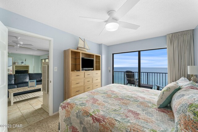 tiled bedroom with access to exterior, a textured ceiling, and ceiling fan