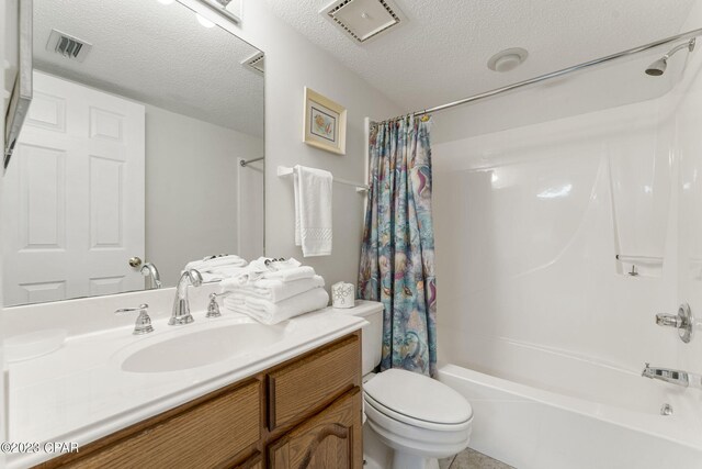 full bathroom featuring vanity, shower / bath combo with shower curtain, a textured ceiling, and toilet