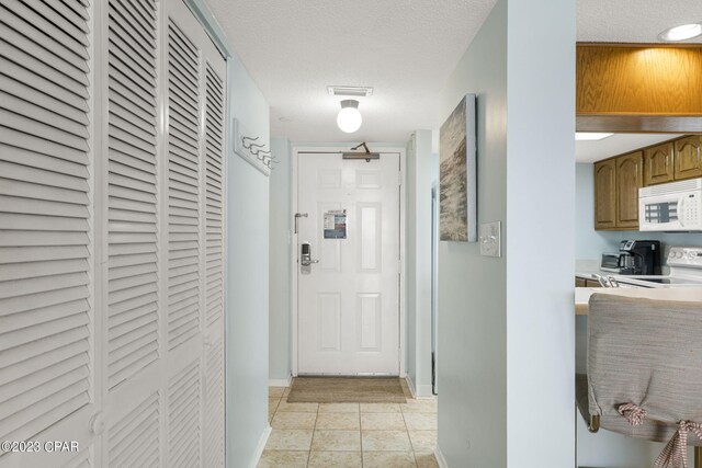 hallway with light tile patterned flooring and a textured ceiling