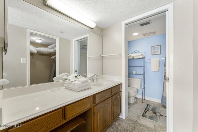 bathroom with tile patterned floors, vanity, a textured ceiling, and toilet