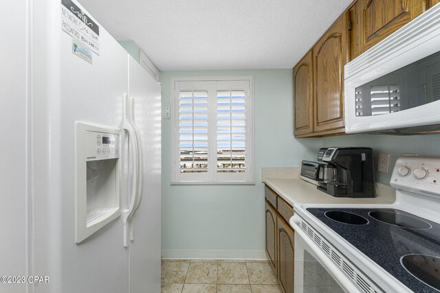 kitchen with a textured ceiling, light tile patterned floors, and white appliances