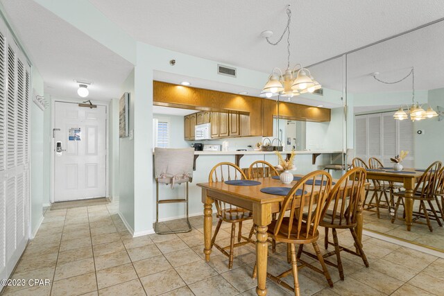 dining room with a notable chandelier, light tile patterned flooring, and a textured ceiling