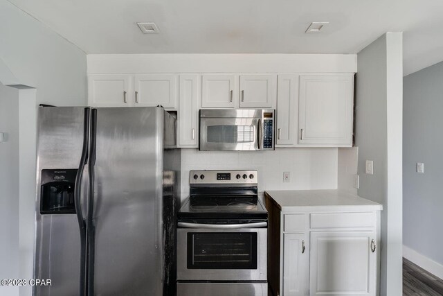 kitchen with dark hardwood / wood-style flooring, appliances with stainless steel finishes, and white cabinets