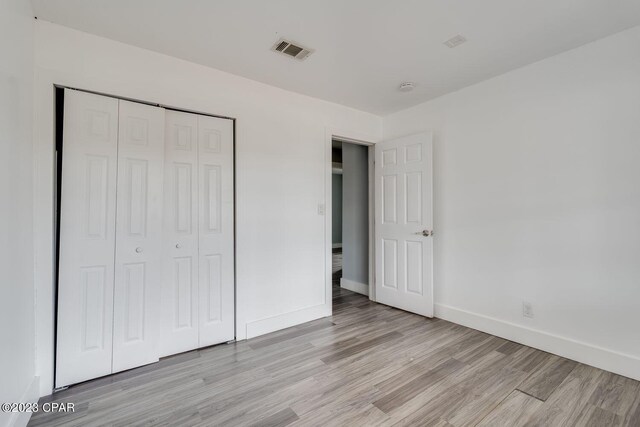 unfurnished bedroom with a closet and light hardwood / wood-style floors