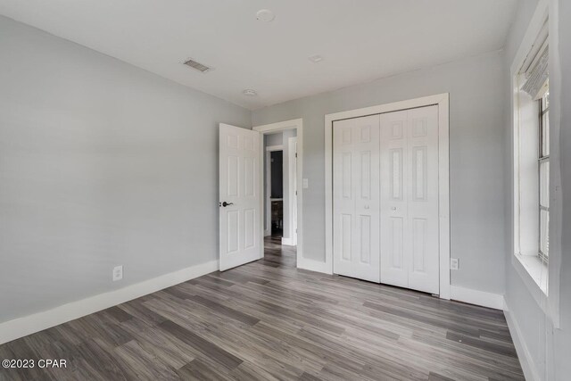 unfurnished bedroom featuring a closet and dark hardwood / wood-style flooring