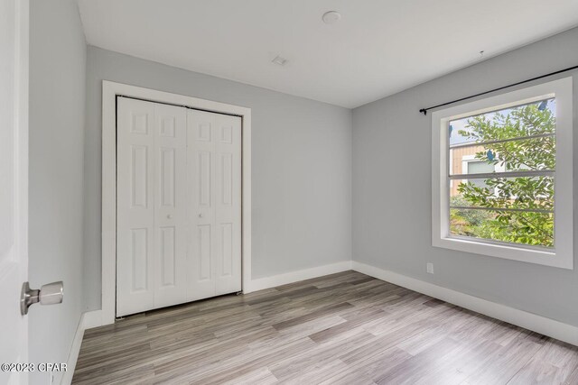 unfurnished bedroom featuring a closet and light hardwood / wood-style flooring