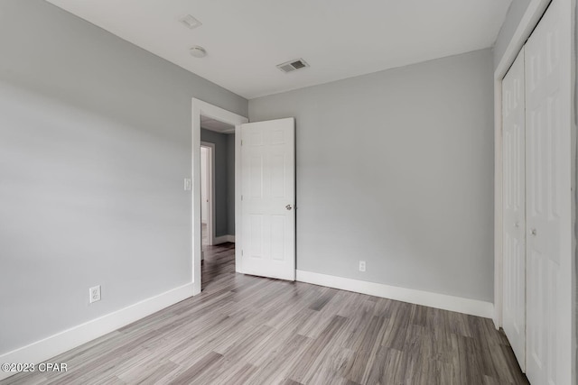 unfurnished bedroom with light wood-type flooring and a closet