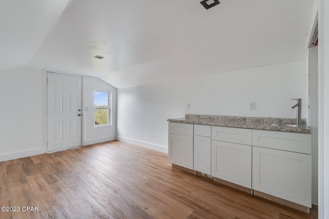 interior space featuring vaulted ceiling, sink, and light hardwood / wood-style floors